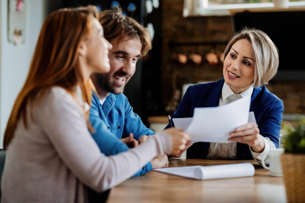 Agente imobiliário sorridente se comunicando com um casal