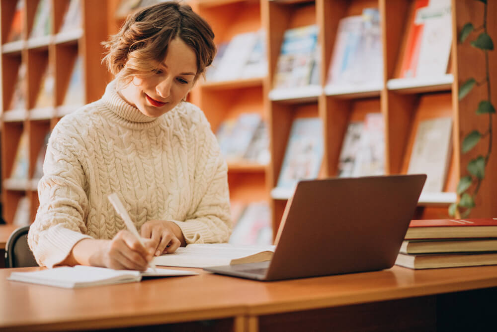 Mulher jovem a trabalhar num portátil numa biblioteca