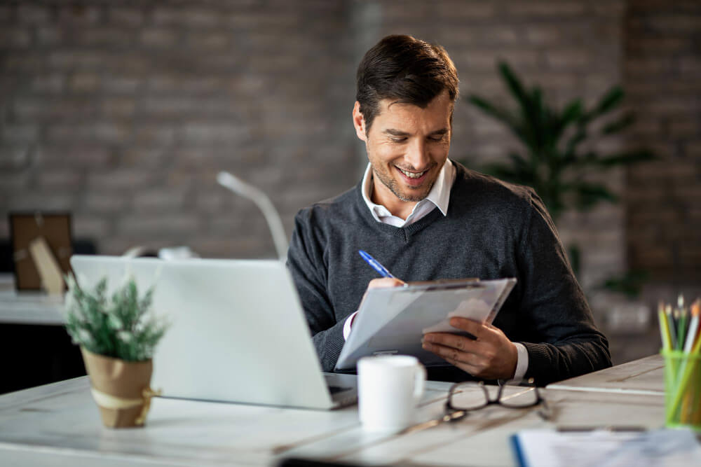 Empreendedor sorridente escrevendo um relatório de negócios